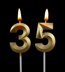 Burning golden birthday candles on black background, number 35	