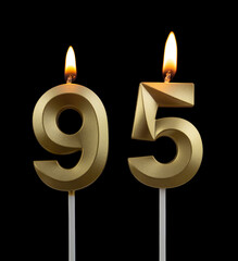 Burning golden birthday candles on black background, number 95	