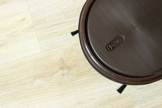Robot Cleaning Home. Automatic Robotic Cleaner On Ground. Overhead Black Robotic Vacuum Cleaner Tidying Tile Floor.