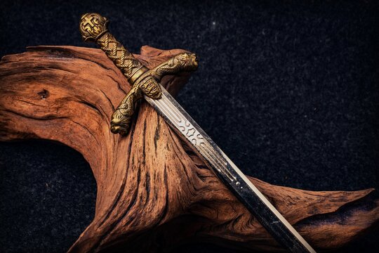 Knight's sword on the background of an old textured wooden driftwood of brown color