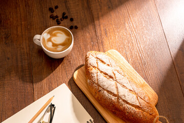 Cup of hot coffee with bread on wood background