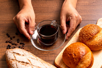 Glass Cup of hot black coffee with bread on wood background