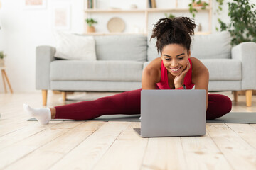 Fit Black Woman Exercising Stretching At Laptop Computer At Home