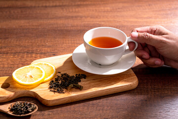 Cup of freshly tea with yellow lemon on black