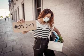 Business woman in face mask holding box with office staff and COVID-19 sign. Coronavirus job cuts