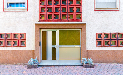 Frontal view of a house with retro style facade, entrance and distinct red windows.