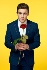 Gentlemen in classic suit on yellow background and red rose romance cropped view model portrait.