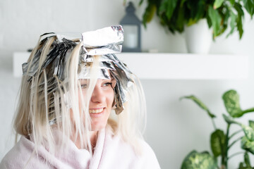 Beautiful young woman with foil on her hair. Bleaching or dyeing process at home