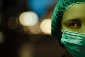 Close view in green light: Tired doctor looks at you during night shift