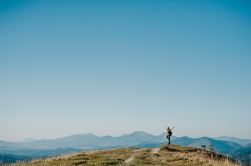 Obraz premium Hiker tourist in the mountains at sunset. Hipster girl with a photo camera and a backpack travels and enjoy nature.