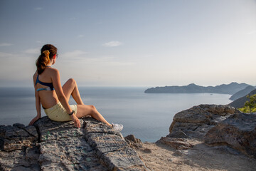A beautiful woman enjoying the sea view from the top of a mountain