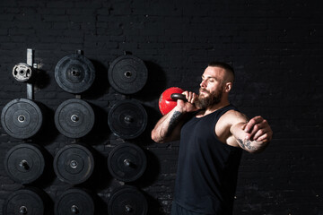 Young sweaty strong muscular fit man with big muscles doing hardcore cross kettlebell snatch...