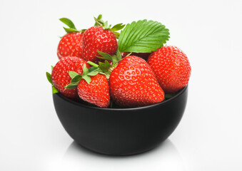 Fresh raw organic strawberries in black ceramic bowl plate on white background. Best summer berries.