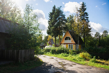 Fototapeta na wymiar A typical russian summer village in the greenery of trees and flowers on a warm sunny day. Country cottages.