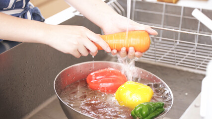 キッチンで野菜を洗う若い女性	
