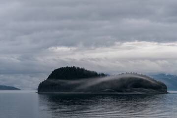 A cloud echos the shape of the island behind it in SE Alaska, USA.