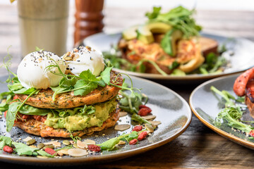 Two poached eggs on top of a vegetable stack at a table set for breakfast