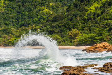 Spectacular water splash formed by wave crashing on rocks in brazilian beach
