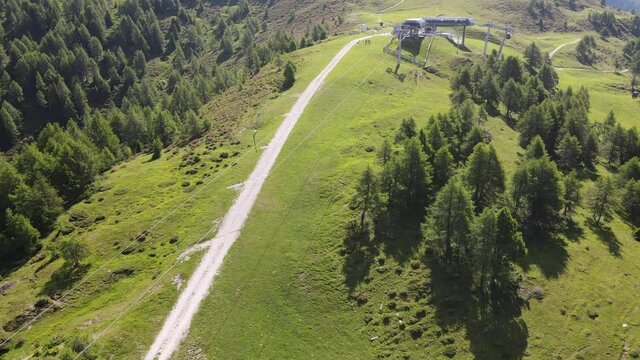 4k video shooting with drone of mountain panoramas, on the italian dolomites alps. snow-capped peaks, green meadows and ski slopes, mountain trails with small wooden houses. blue skies with clouds.