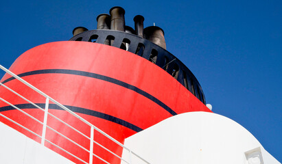 Red and black funnel of classic ocean liner or cruise ship or cruiseship against deep blue sky...