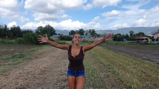 ragazza corre verso la telecamera ridendo e con le braccia aperte