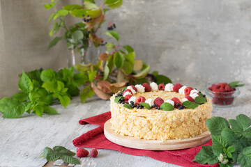 Napoleon cake with raspberries and cream on red napkin on grey wooden background. Selective focus