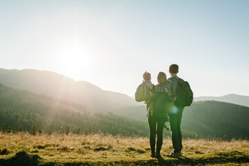 The daughter hug parents on nature. Mom, dad, and child walk in the grass. Family spending time...