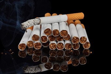 Several whole cigarettes and one smoking cigarette on a black background.