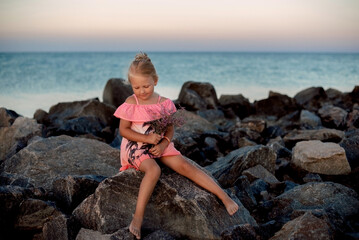 child girl seat on the rock on beach with sea backgrond