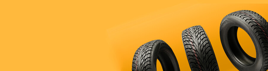 three friction tires, winter season re-booting, on a bright orange background. copy space panorama for the site header © Vladimir Razgulyaev