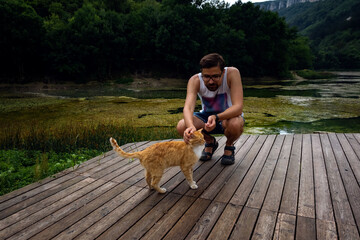 A man is playing with a domestic red tabby cat.