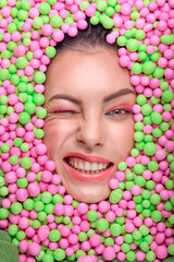 Obraz na płótnie Canvas Face of beautiful young woman with creative makeup surrounded by different sweets