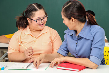 Asian disabled children Or, an autistic child learns to read, write and train their hand and finger muscles with a teacher at their classroom desk.