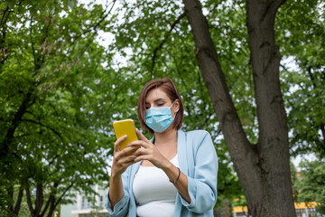 Woman with face mask using phone outdoor stock photo
