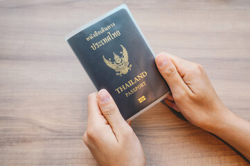 Someone hands holding a Thailand passport in book cover before take a flight.