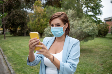 Woman with face mask using phone outdoor stock photo
