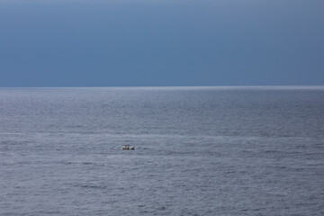 Obraz premium small boat at rough sea and windy weather, cloudy.