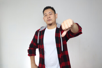 Portrait young asian man wearing casual shirt shows upset expression with thumbs down