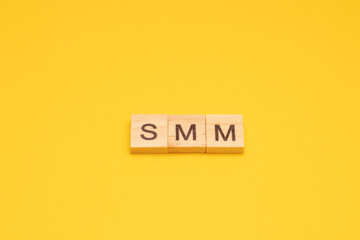 The word SMM made from wooden cubes on a yellow background