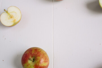 Flat-lay concept of red apples on a white wooden background, view from above, half apples
