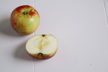 Flat-lay concept of red apples on a white wooden background, view from above, half apples