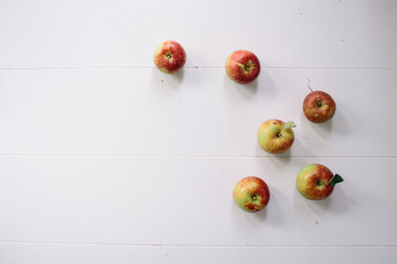 Flat-lay concept of red apples on a white wooden background, view from above, half apples