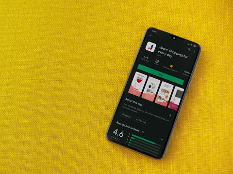 Lod, Israel - July 8, 2020: Joom app play store page on the display of a black mobile smartphone on a yellow fabric background. Top view flat lay with copy space.