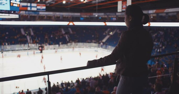 Girl watching sports on hockey arena. Slow motion. Female hockey fan.