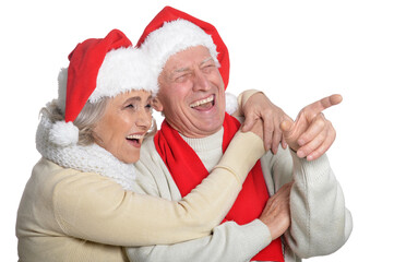 Portrait of happy senior couple in Santa hats pointing