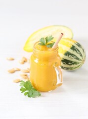 Pumpkin smoothie in a glass jar with bamboo straws on a light background