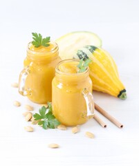 Pumpkin smoothie in a glass jar with bamboo straws on a light background