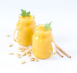 Pumpkin smoothie in a glass jar with bamboo straws on a light background