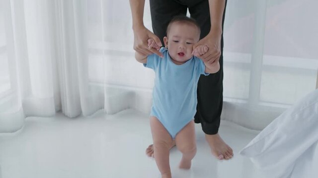 Family concept. The mother was supporting the baby to walk in the house. 4k Resolution.