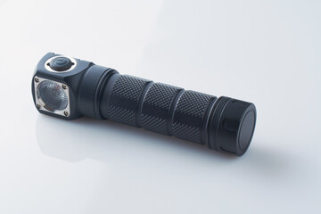 Electric LED torch isolated on white background. Black metal Flashlight or pocket lamp for camping dark time. Modern LED lamp with bright projection.